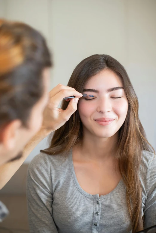 a woman getting her eyebrows done in front of a mirror, jen atkin, natural make-up, te pae, cut lines