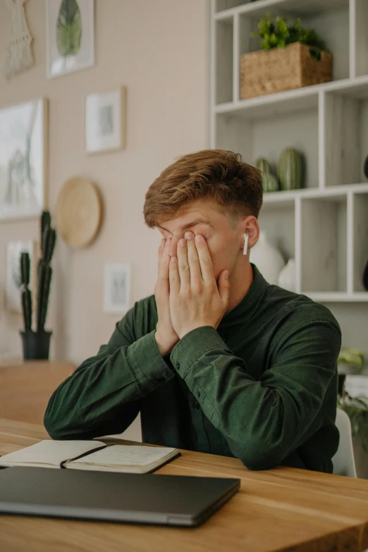 a man sitting at a table with his hands on his face, trending on pexels, in an office, boy with neutral face, shut eyes, instagram post