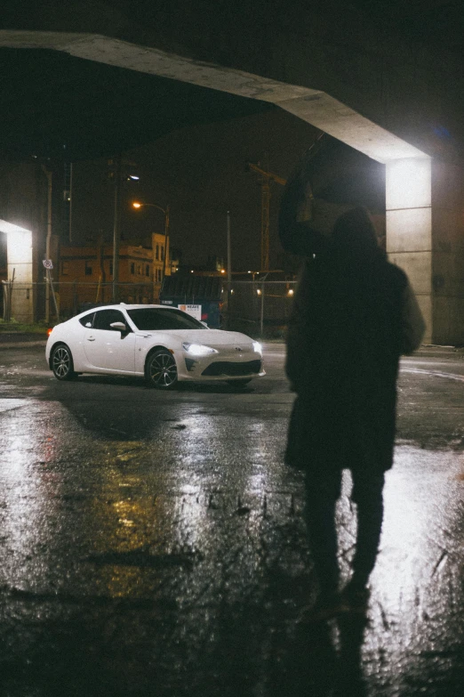 a man standing in the rain next to a white car, inspired by Elsa Bleda, pexels contest winner, renaissance, toyota supra, white on black, on the concrete ground, hq 8k cinematic