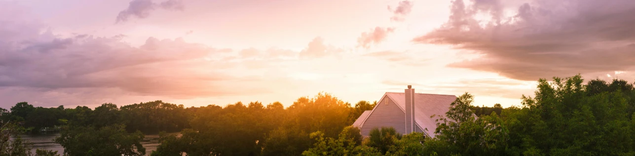 a house sitting on top of a lush green hillside, by Carey Morris, unsplash, pink sunlight, southern gothic, profile image, sunset panorama