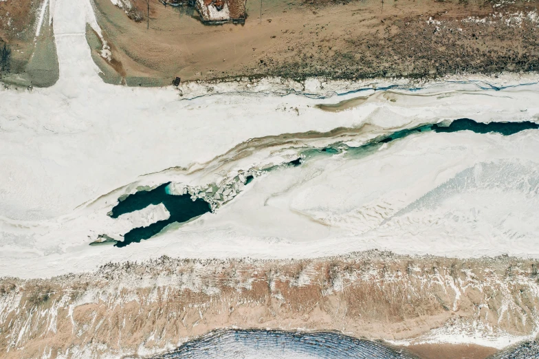 a large body of water sitting on top of a sandy beach, by Daniel Lieske, trending on unsplash, land art, covered in ice, satellite imagery, thumbnail, wyoming