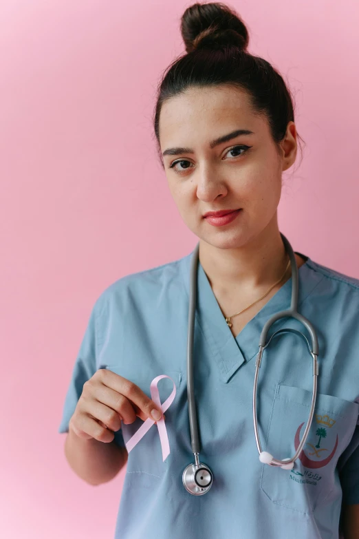 a woman in a blue scrub suit holding a pink ribbon, a colorized photo, pexels contest winner, isabela moner, anna nikonova aka newmilky, medical reference, 8