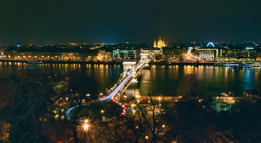 a view of a bridge over a river at night, by Adam Szentpétery, pexels contest winner, bird's eye view of a city, holiday season, budapest street background, thumbnail