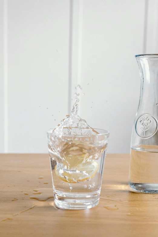 a pitcher and a glass of water on a table, inspired by Géza Dósa, splashes, with lemon skin texture, medium - shot, infused