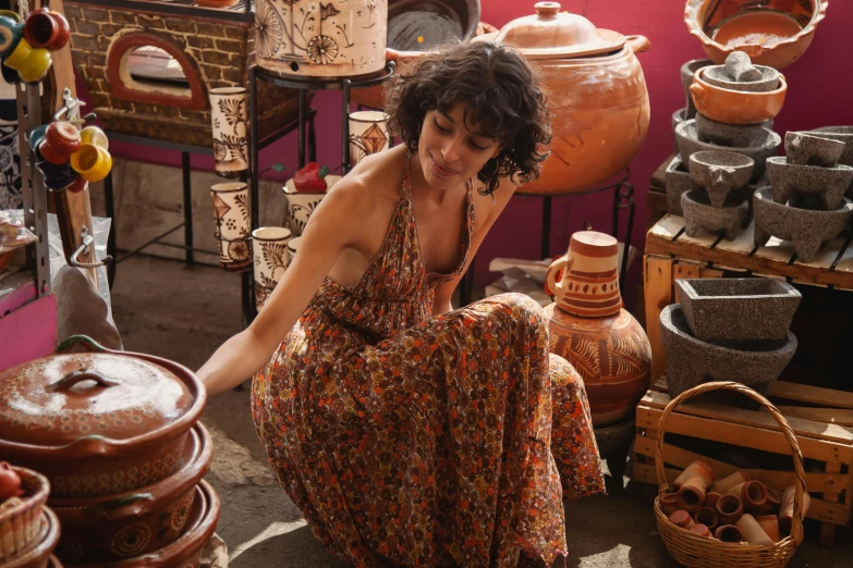 a woman sitting in a room filled with pots and pans, pexels contest winner, renaissance, female figure in maxi dress, middle eastern style vendors, amphora, morena baccarin