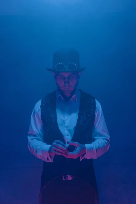 a man standing in front of a blue background, a hologram, unsplash, magical realism, top hats, eerie atmospheric lighting, ( ( theatrical ) ), submerged dramatic