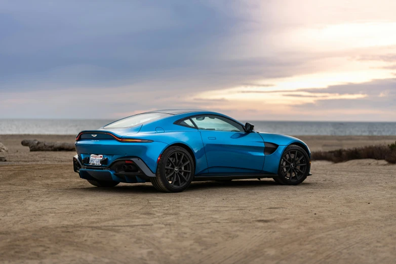 a blue sports car parked on a beach, by Austin English, pexels contest winner, renaissance, aston martin, profile view perspective, f12, glossy surface