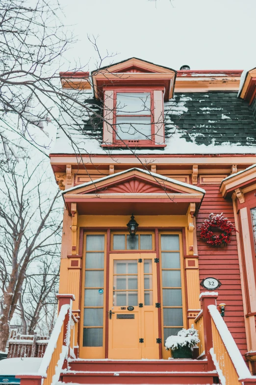 a red house with a yellow door in the snow, inspired by Wes Anderson, pexels contest winner, art nouveau, quebec, victorian house, multicolored, brown