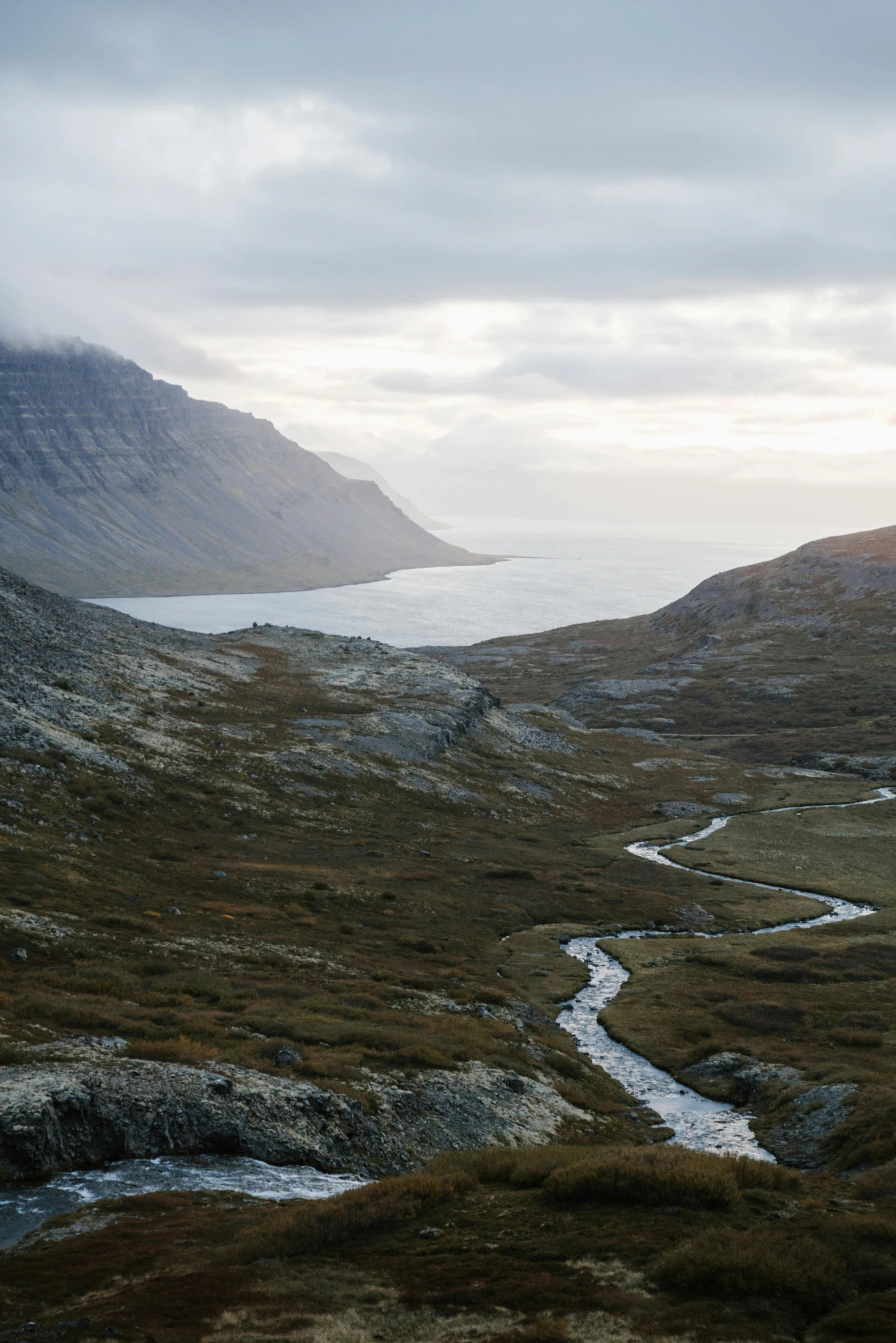 a river running through a valley next to a mountain, overlooking the ocean, jörmungandr, barren landscape, explore