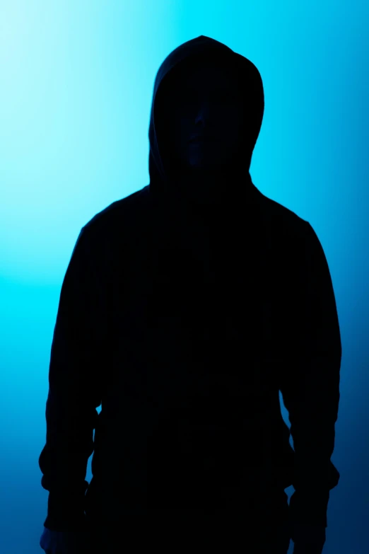 a silhouette of a person in a hoodie, by James Morris, blue backdrop, ( ( photograph ) ), promo image, ominous photo