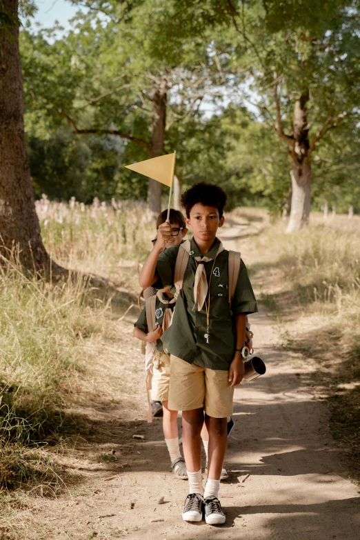 a couple of kids walking down a dirt road, wes anderson film, scout boy, on forest path, maximus jacobs