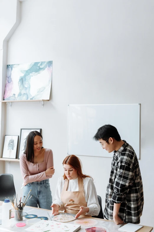 a group of people standing around a table, trending on pexels, academic art, in an office, asian female, white space in middle, on display