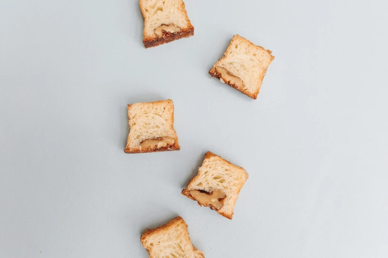 a number of pieces of bread on a white surface, by Nicolette Macnamara, unsplash, minimalism, caramel, battle toast, narrow shot, frontal shot