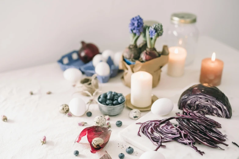 a table that has a bunch of food on it, a still life, inspired by Eden Box, trending on pexels, white and purple, easter, indigo and venetian red, seeds