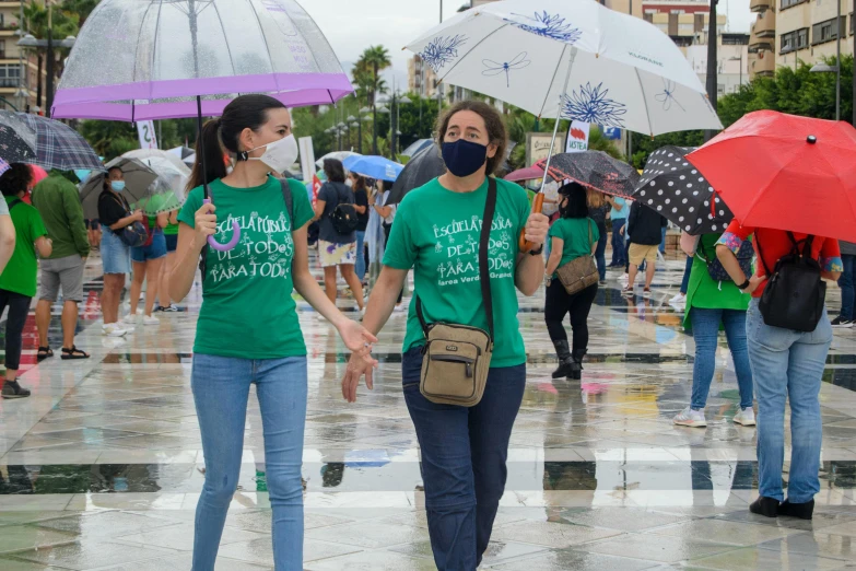 a group of people walking down a street holding umbrellas, by Amelia Peláez, shutterstock, antipodeans, wearing green clothing, two women kissing at a carnival, 5 k, 2 0 2 2 photo