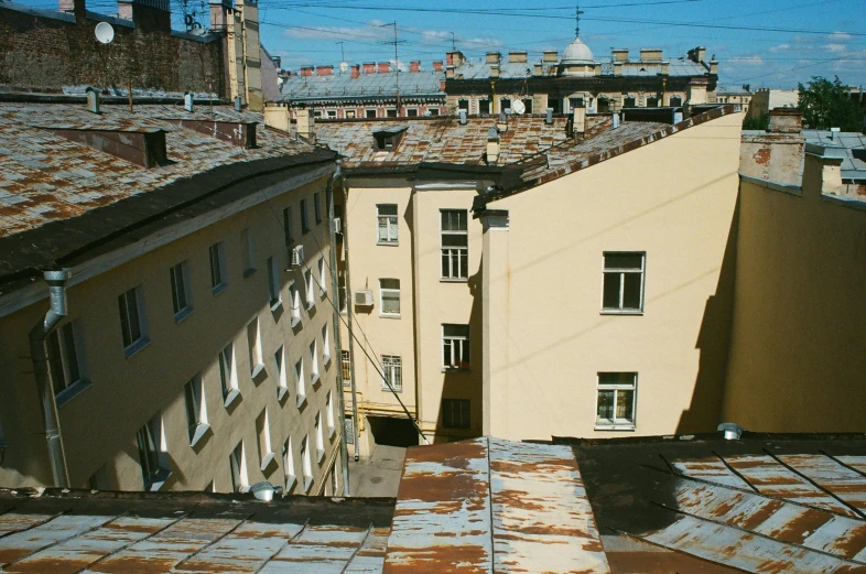 a couple of buildings that are next to each other, an album cover, inspired by Illarion Pryanishnikov, unsplash, post - soviet courtyard, roofs, 2 0 0 0's photo, afternoon light