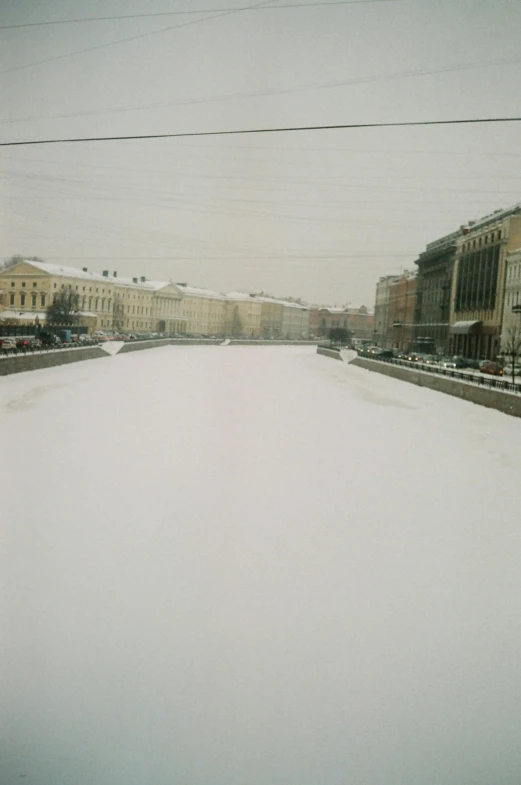 a street filled with lots of snow next to tall buildings, an album cover, inspired by Vasily Surikov, socialist realism, in empty!!!! legnica, canal, saint petersburg, disposable camera photograph