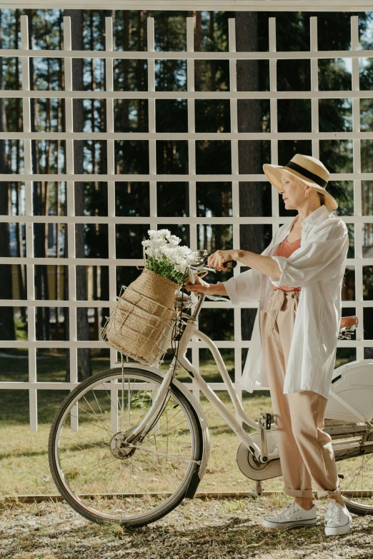 a woman standing next to a bicycle with a basket on it, pexels contest winner, white suit and hat, wearing a linen shirt, al fresco, inspect in inventory image