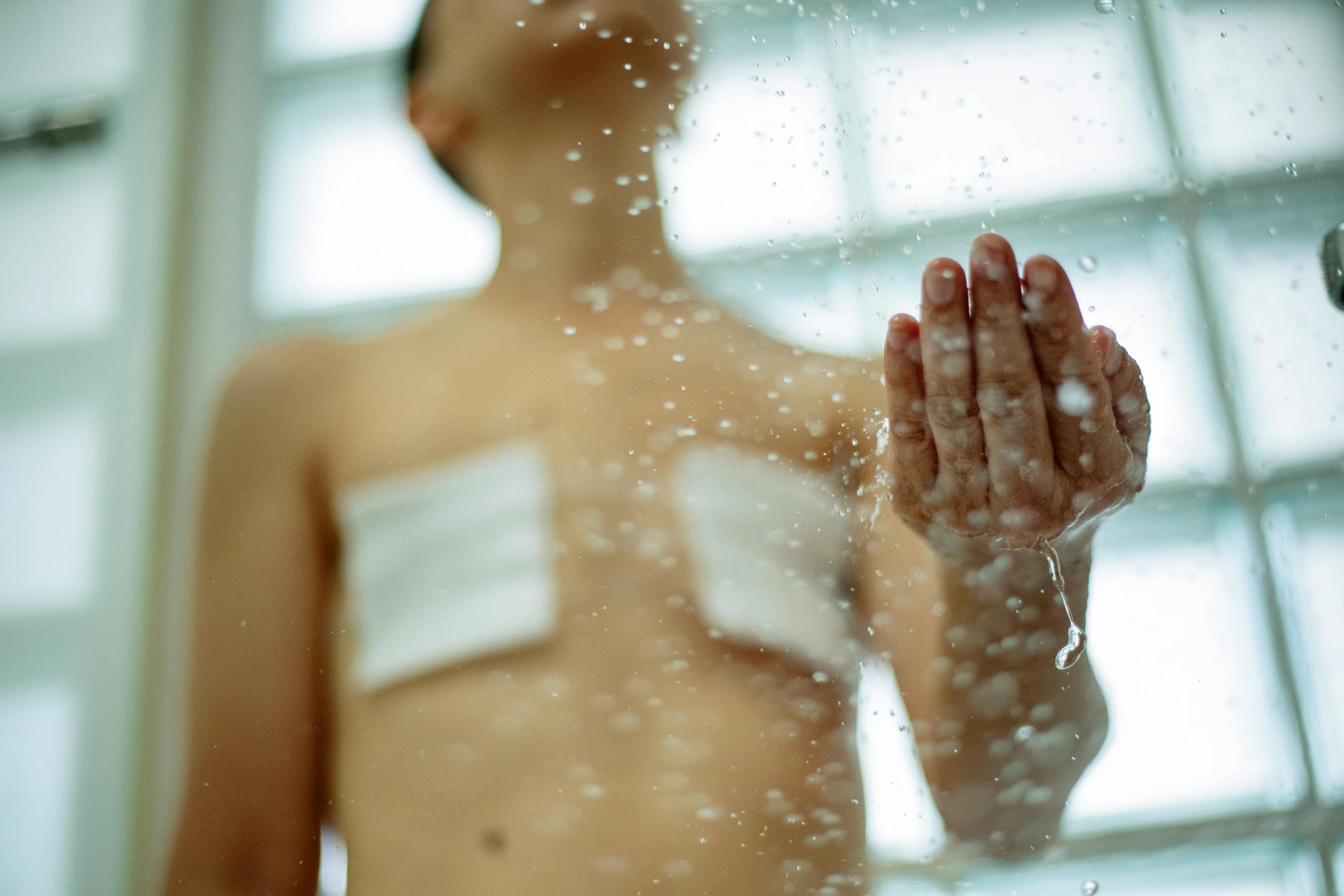 a man with bandages standing in front of a shower, by Julia Pishtar, unsplash, hurufiyya, beads cross onbare chest, emanating magic from her palms, hospital, thumbnail