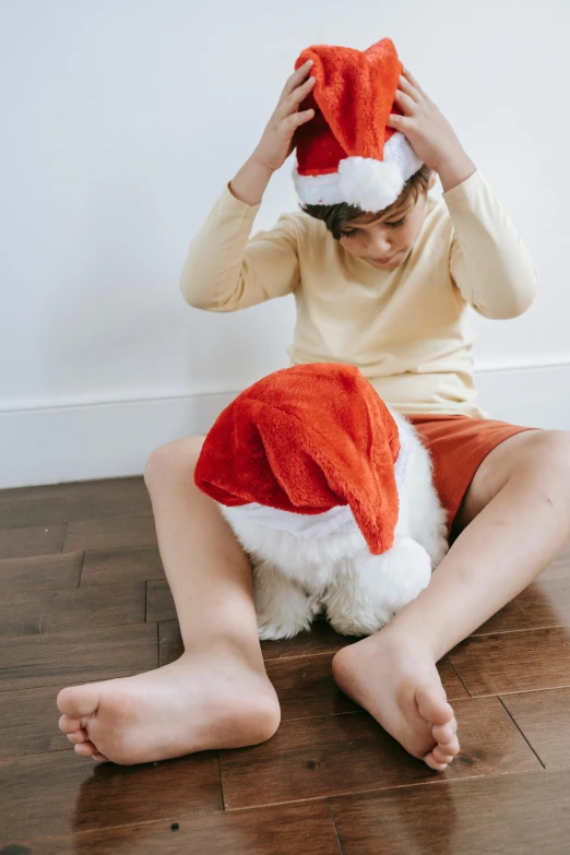 a little girl sitting on the floor with a santa hat on her head, incoherents, light over boy, jellycat, full product shot, looking down