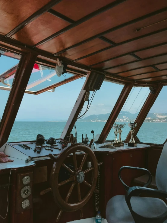 a close up of a steering wheel on a boat, by Kristian Zahrtmann, pexels contest winner, renaissance, window with rio de janeiro view, wide shot of a cabin interior, thumbnail, queen of the sea mu yanling