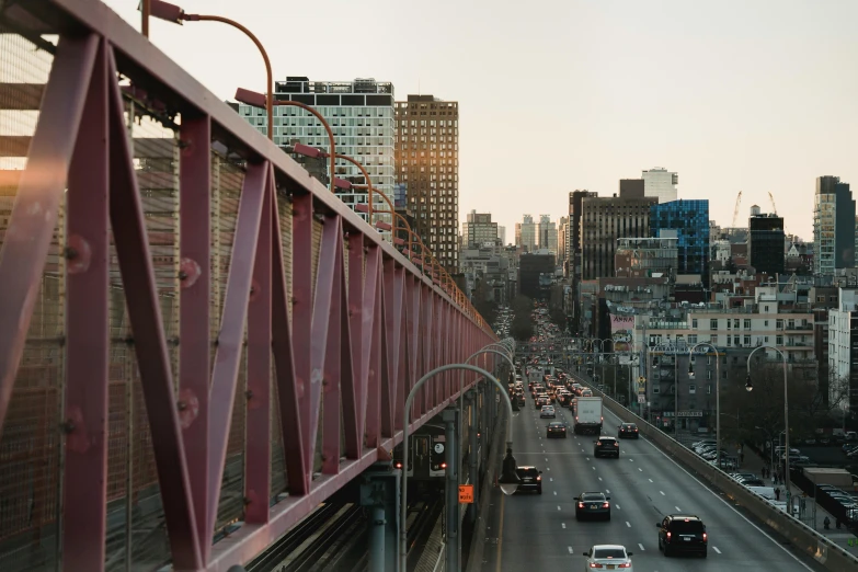 a street filled with lots of traffic next to tall buildings, inspired by Thomas Struth, unsplash contest winner, renaissance, metallic bridge, hell gate, red trusses, portra 8 0 0 ”