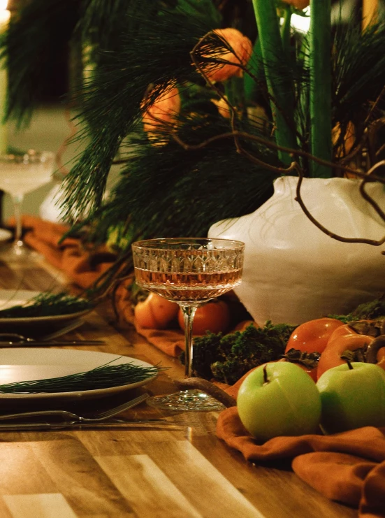 a wooden table topped with plates and glasses, by Carey Morris, unsplash, renaissance, evergreen branches, apple orange, profile image, christmas night