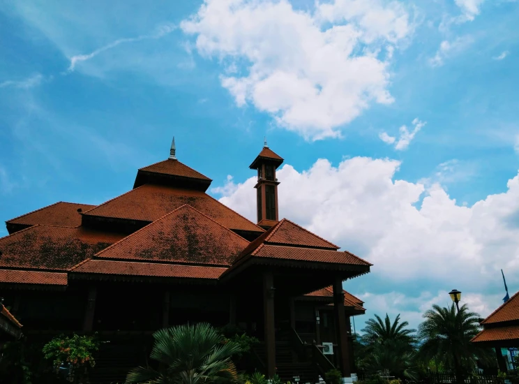 a large building with a clock on top of it, an album cover, by Bernardino Mei, pexels contest winner, hurufiyya, holiday resort, malaysian, tiled roofs, clouded sky