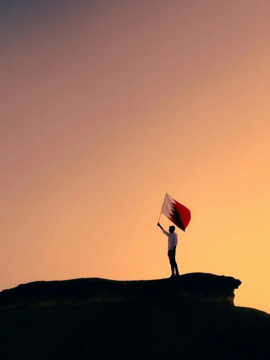 a person standing on top of a hill holding a flag, by Julia Pishtar, pexels contest winner, arabia, crimson themed, with arms up, 🚿🗝📝