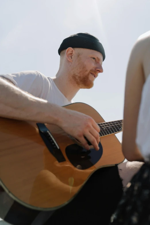 a man playing a guitar next to a woman, one is a redhead, paul barson, high res photograph, video