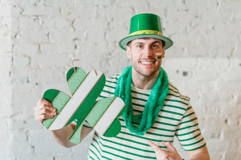 a man wearing a green hat and a green scarf, inspired by Mór Than, pexels contest winner, wearing stripe shirt, cardboard cutout, clover, wooden