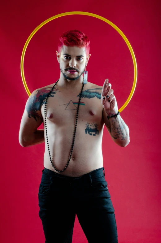 a man with red hair standing in front of a red background, an album cover, inspired by Randy Vargas, pexels, tribal piercing and tatoos, gay pride, belly, circle pit