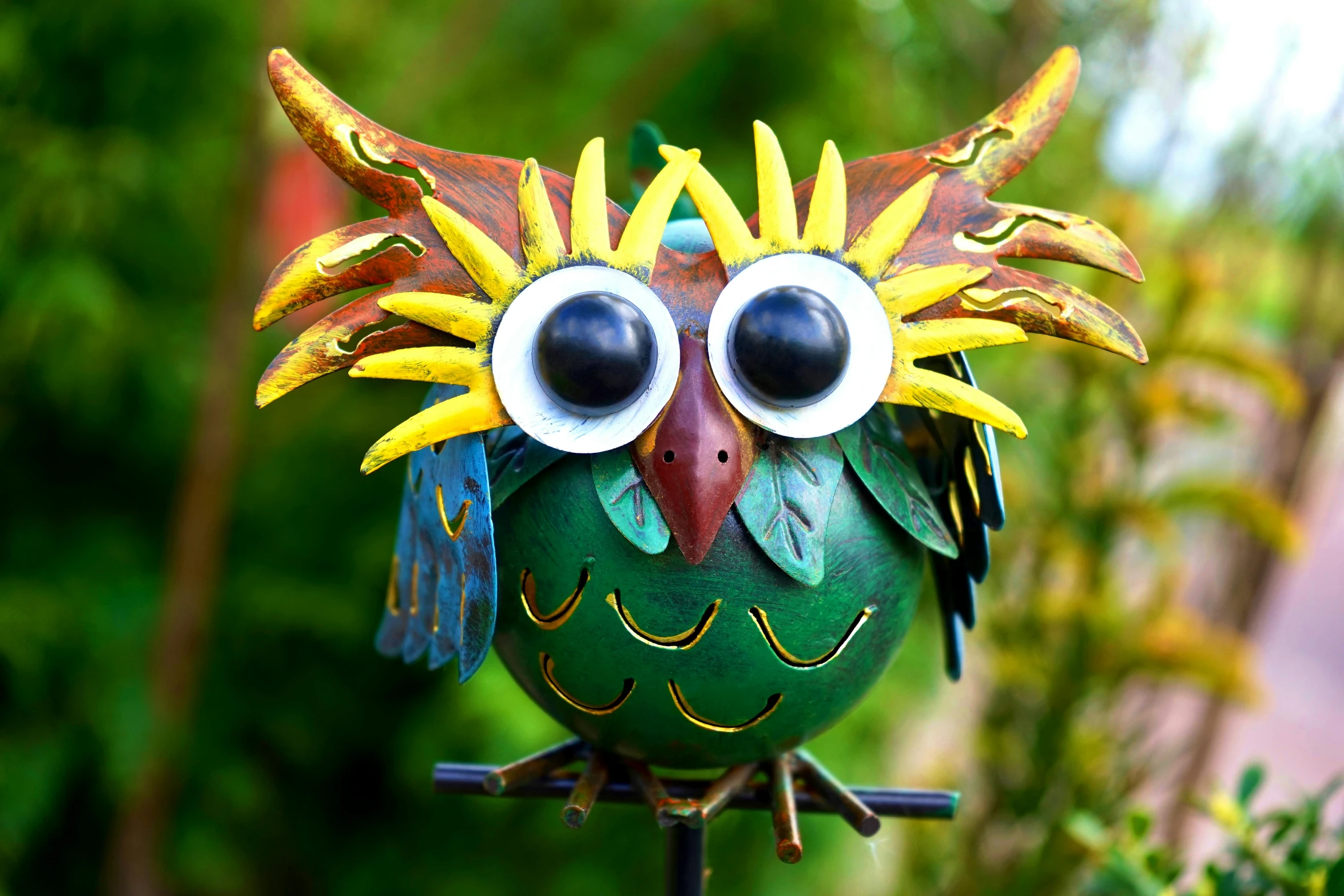 a colorful bird sitting on top of a metal pole, new sculpture, cute round green slanted eyes, owl mask, magical garden plant creatures, face shown