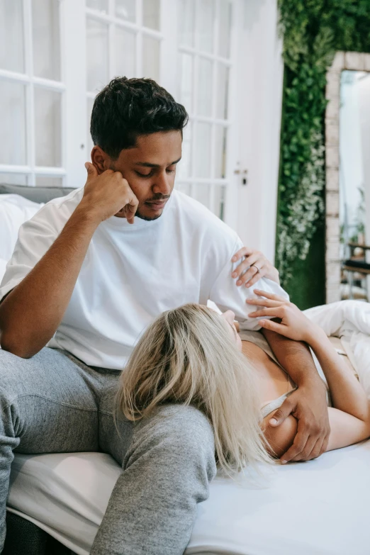 a man sitting on top of a bed next to a woman, by Cosmo Alexander, trending on pexels, crying and reaching with her arm, relaxing on the couch, te pae, smug look