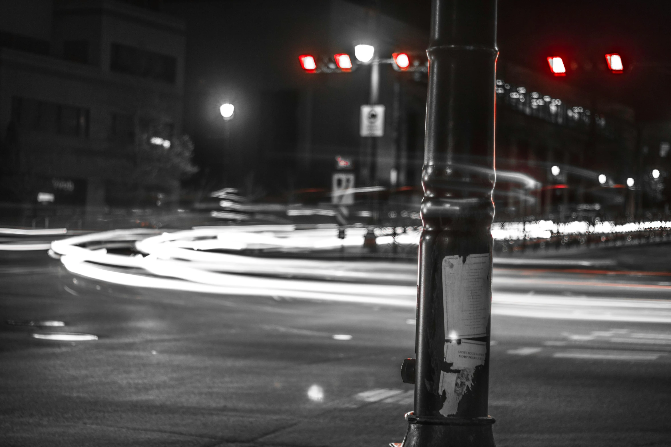 a black and white photo of a street at night, a black and white photo, pexels contest winner, realism, red lights, traffic light, streetlamp, color splash