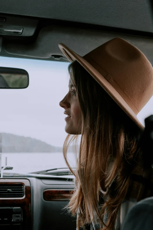 a woman sitting in the passenger seat of a car, by Jessie Algie, trending on unsplash, tall hat, girl with brown hair, headshot profile picture, standing straight