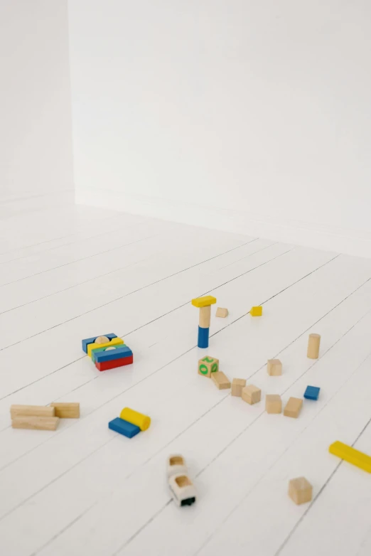 a pile of wooden blocks sitting on top of a white floor, in a white room, playing games, subtle detailing, primary colors are white