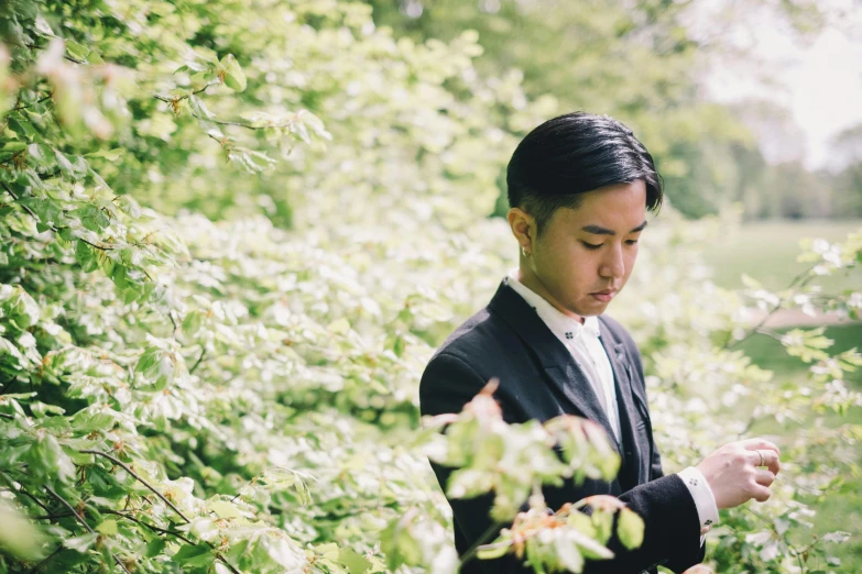 a man in a suit looking at his cell phone, an album cover, unsplash, romanticism, in a verdant garden, ruan jia and brom, groom, avatar image