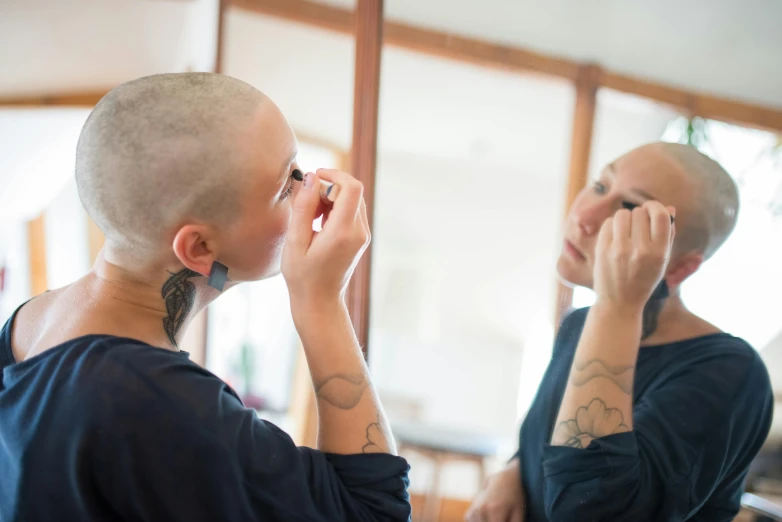 a woman brushing her hair in front of a mirror, by Jacqui Morgan, pexels contest winner, brown buzzcut, detailed makeup on eyes, lachlan bailey, te pae