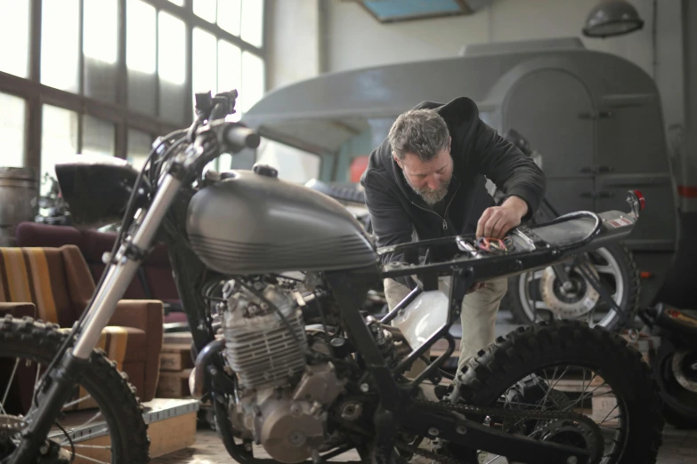a man working on a motorcycle in a garage, 9 9 designs, fan favorite, small manufacture, tight shot