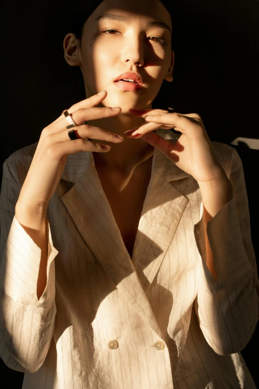 a woman smoking a cigarette in a dark room, an album cover, inspired by Elsa Bleda, trending on pexels, photorealism, wearing two metallic rings, woman in business suit, summer morning light, sleek hands