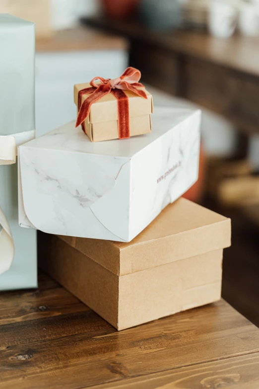 a stack of boxes sitting on top of a wooden table, holding gift, polished white marble, thumbnail