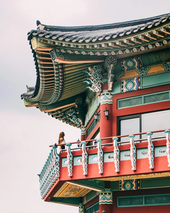 a red and green building with a clock on top of it, inspired by jeonseok lee, trending on unsplash, cloisonnism, in balcony of palace, colourful biomorphic temple, she is korean, conde nast traveler photo