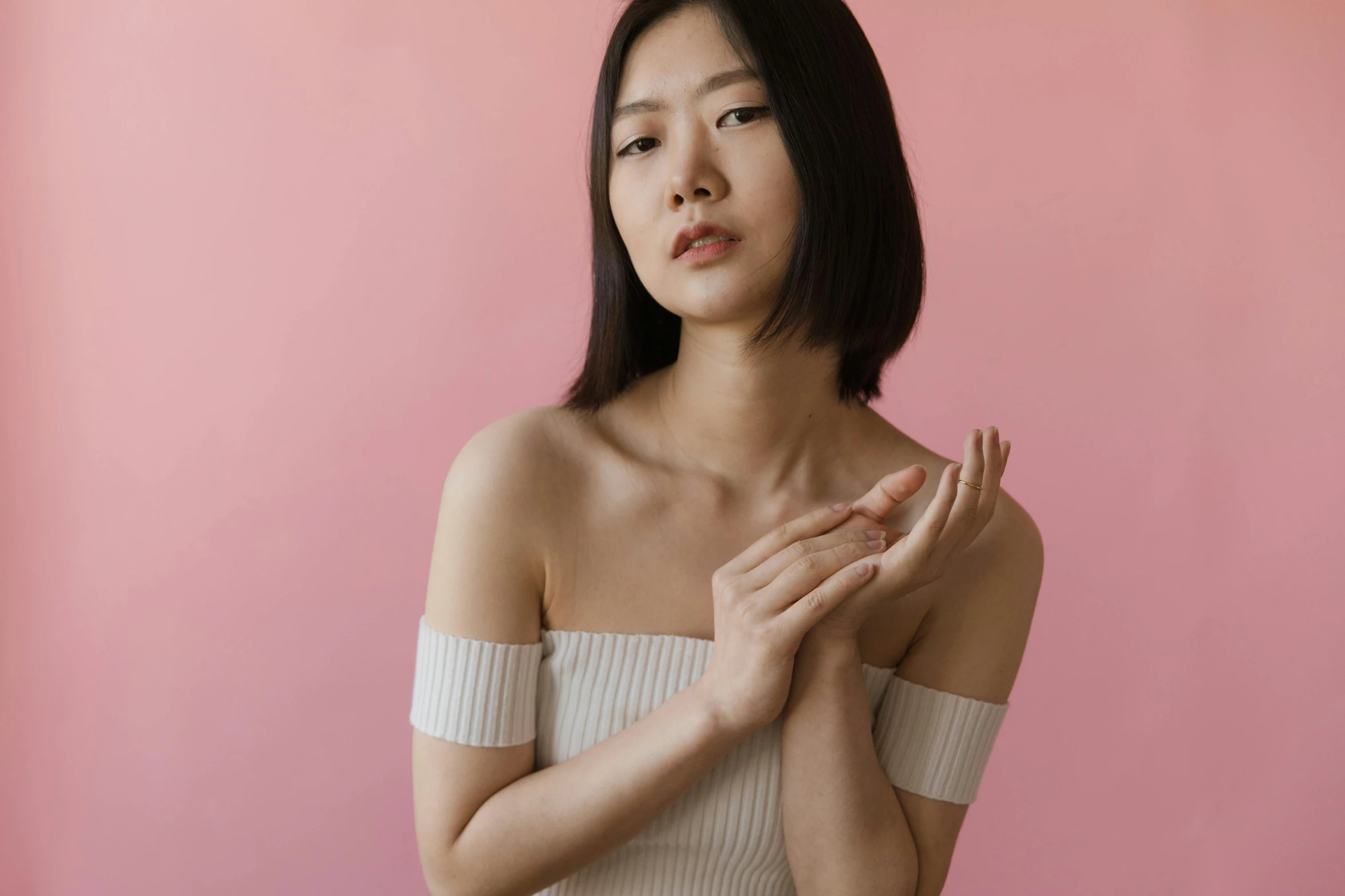 a woman standing in front of a pink wall, inspired by Kim Tschang Yeul, trending on pexels, aestheticism, white bandages on fists, ethnicity : japanese, decolletage, on a pale background