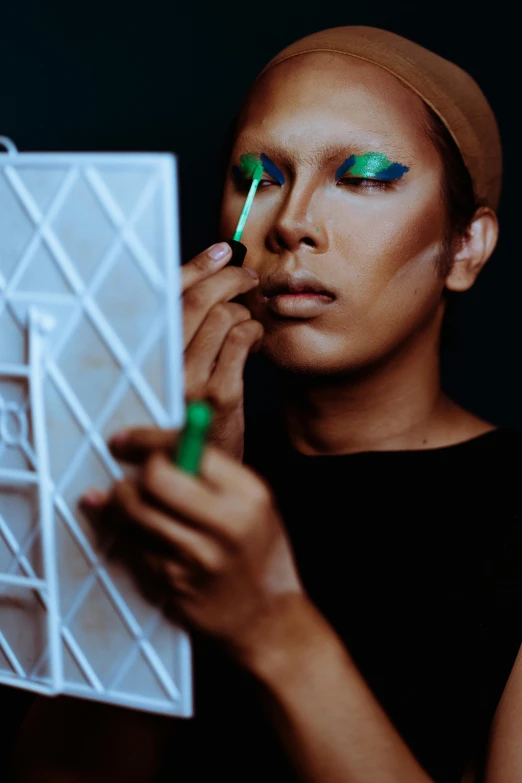 a woman putting on makeup in front of a mirror, an album cover, by Julia Pishtar, unsplash, visual art, eye color green, male model, a portrait of issey miyake, drag