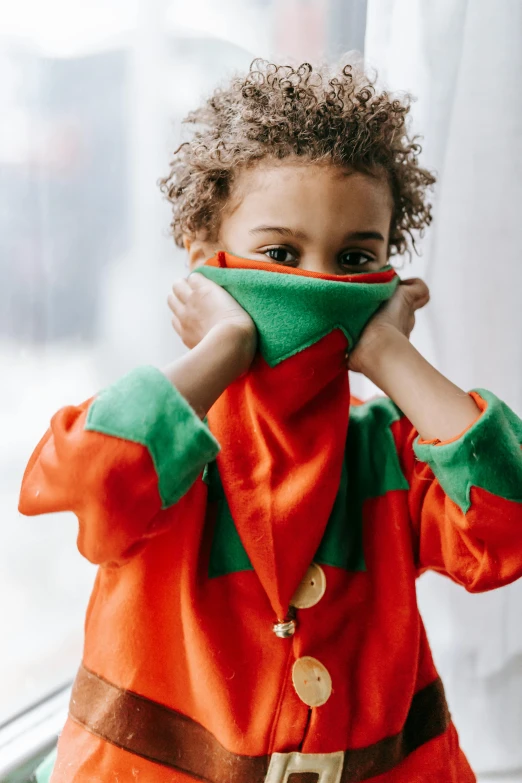 a little boy dressed up as a santa clause, inspired by Raphael, trending on unsplash, orange and green power, male jester, hiding, wearing turtleneck