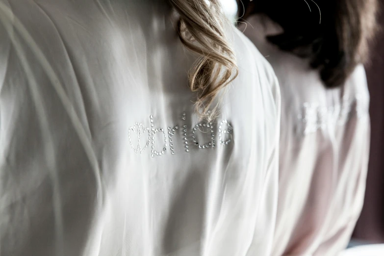 a close up of a woman wearing a white robe, swarovski crystals, with names, high detail clothing, wearing shirts