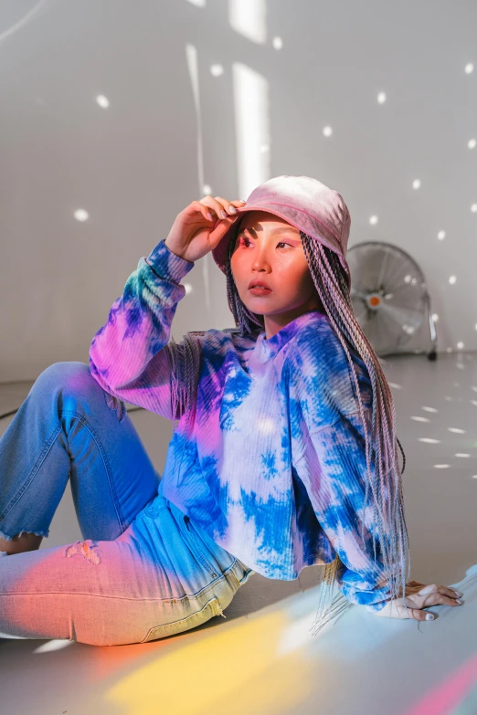 a woman sitting on the floor in a room, inspired by Kim Tschang Yeul, trending on pexels, holography, hat and hoodie, wearing a tie-dye shirt, kda and sam yang, photo from a promo shoot