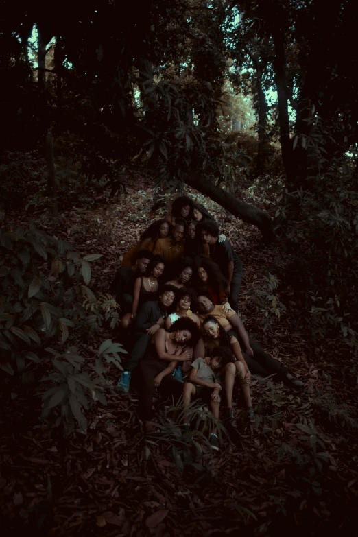 a group of people sitting next to each other in the woods, an album cover, by Elsa Bleda, unsplash, sumatraism, brown skin, motherly, ignant, high view