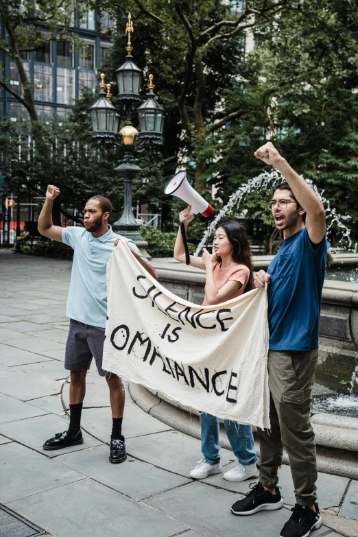 a group of people holding a banner in front of a fountain, by Everett Warner, unsplash contest winner, attacking nyc, 3 - piece, silence, science